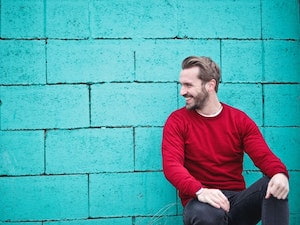 man sitting against a wall smiling