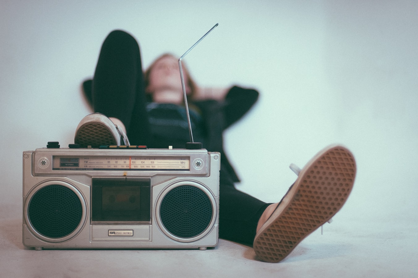 A woman laying and listening to music from an older radio