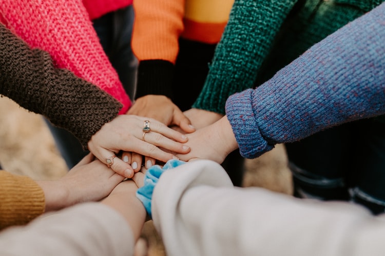 A group of women putting their hands together as a sign of support through the recovery journey
