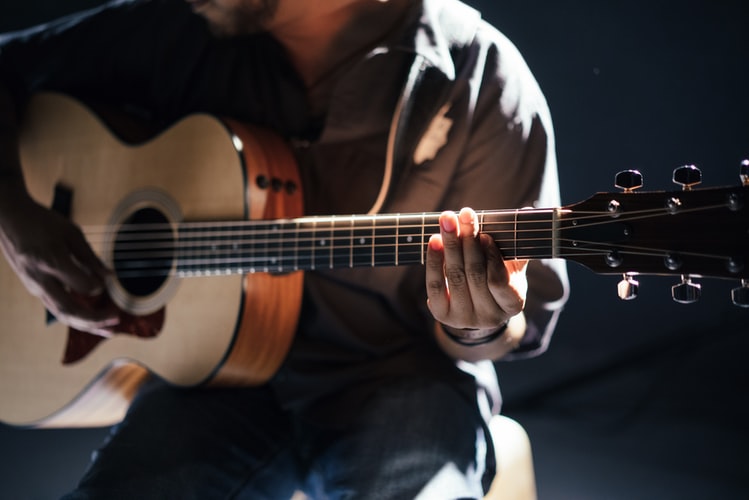 A man playing a guitar. There are many recovery songs that individuals struggling with addiction can listen and relate to