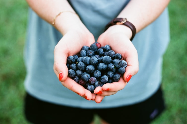 A woman holding blueberries. Eating healthy foods, staying in shape, and monitoring alcohol consumption can help lower the risk for alcohol-related cancers