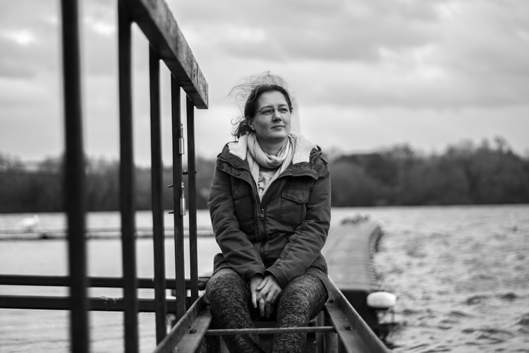 A woman sitting near a lake and thinking about how alcohol rehab programs can help prevent alcohol-related cancers