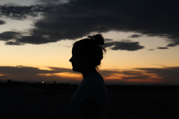 A woman standing outside at night watching the sunset