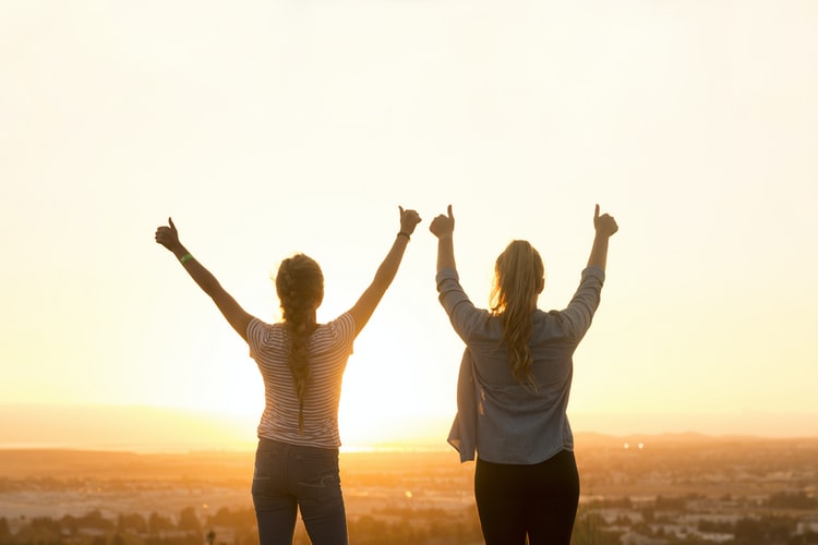 Two women holding their thumbs up as a sign of daily motivation