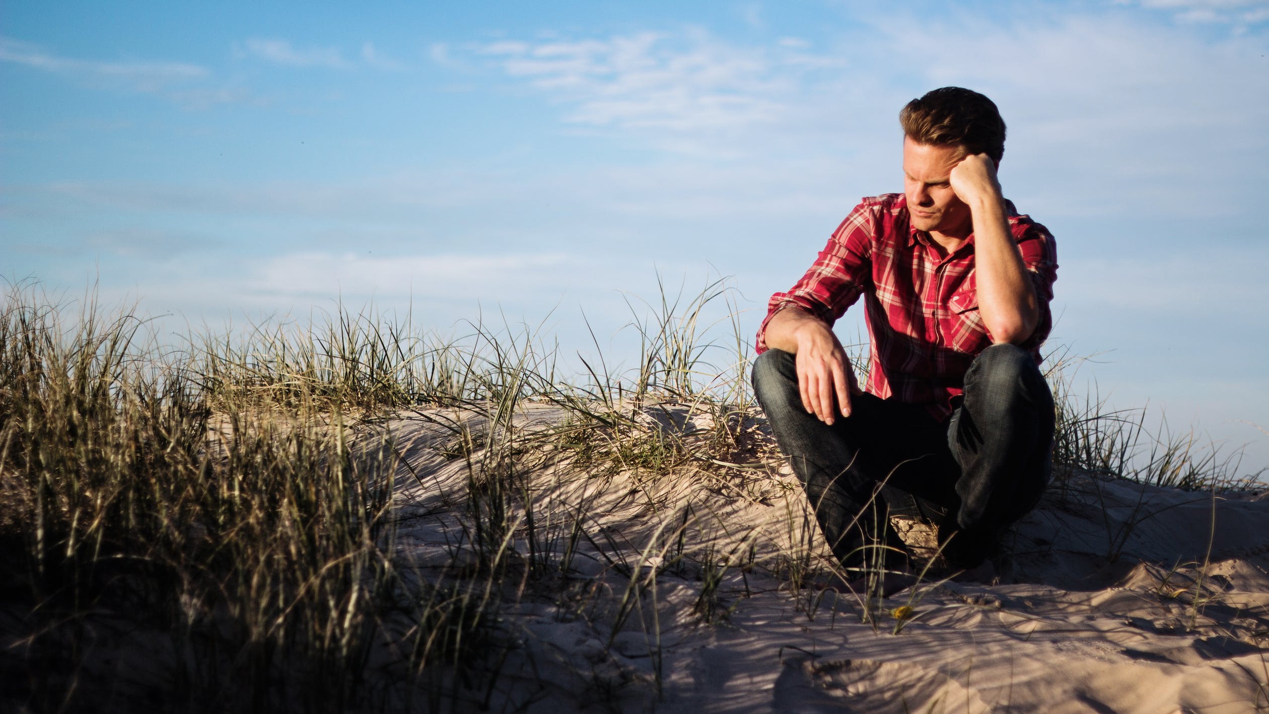 A man sitting on a beach and thinking if he is an alcoholic