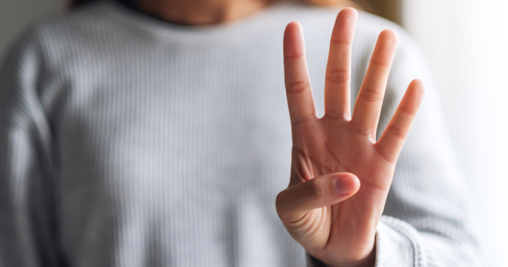 A woman holds up four fingers. The four represents the four points in smart recovery