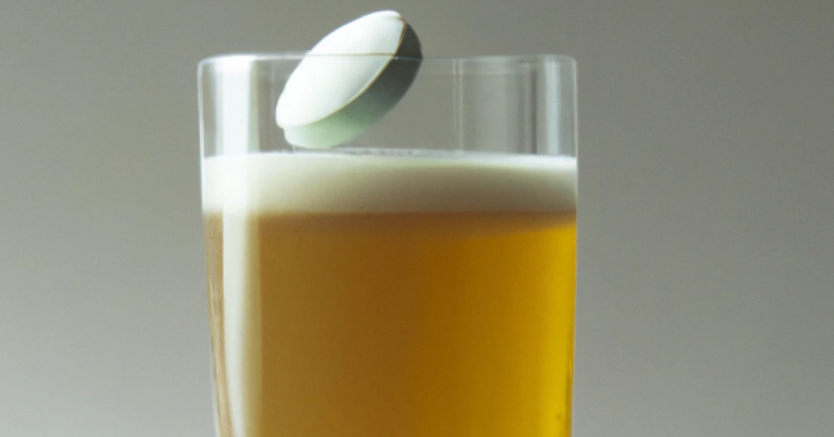 A white pill dropping into a glass of beer.