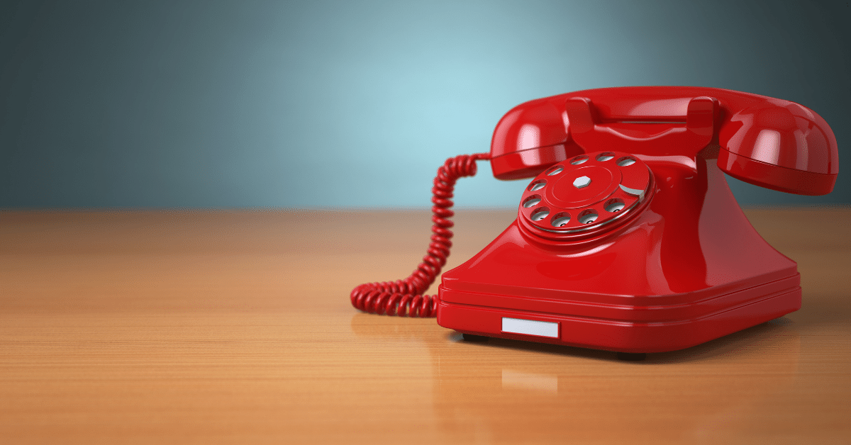 A red phone sits on a desk as the archetypal 