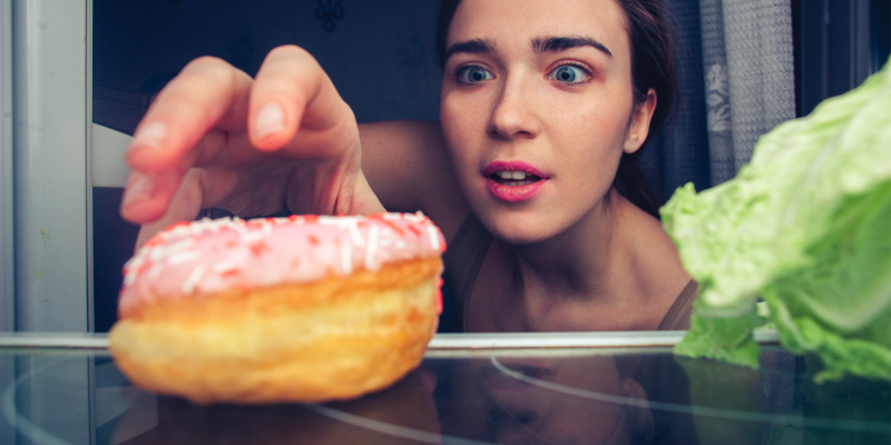 A woman in addiction recovery reaches for a donut to satisfy her sugar craving