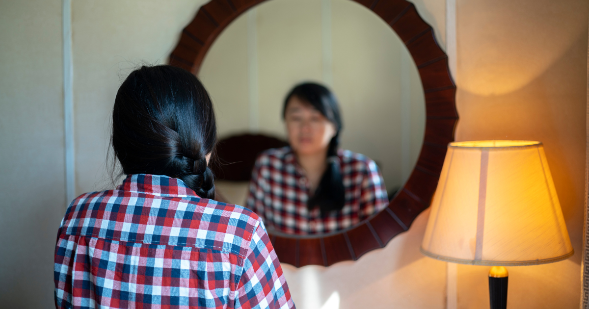A woman struggles with her reflection in the mirror after realizing she struggles with drug addiction