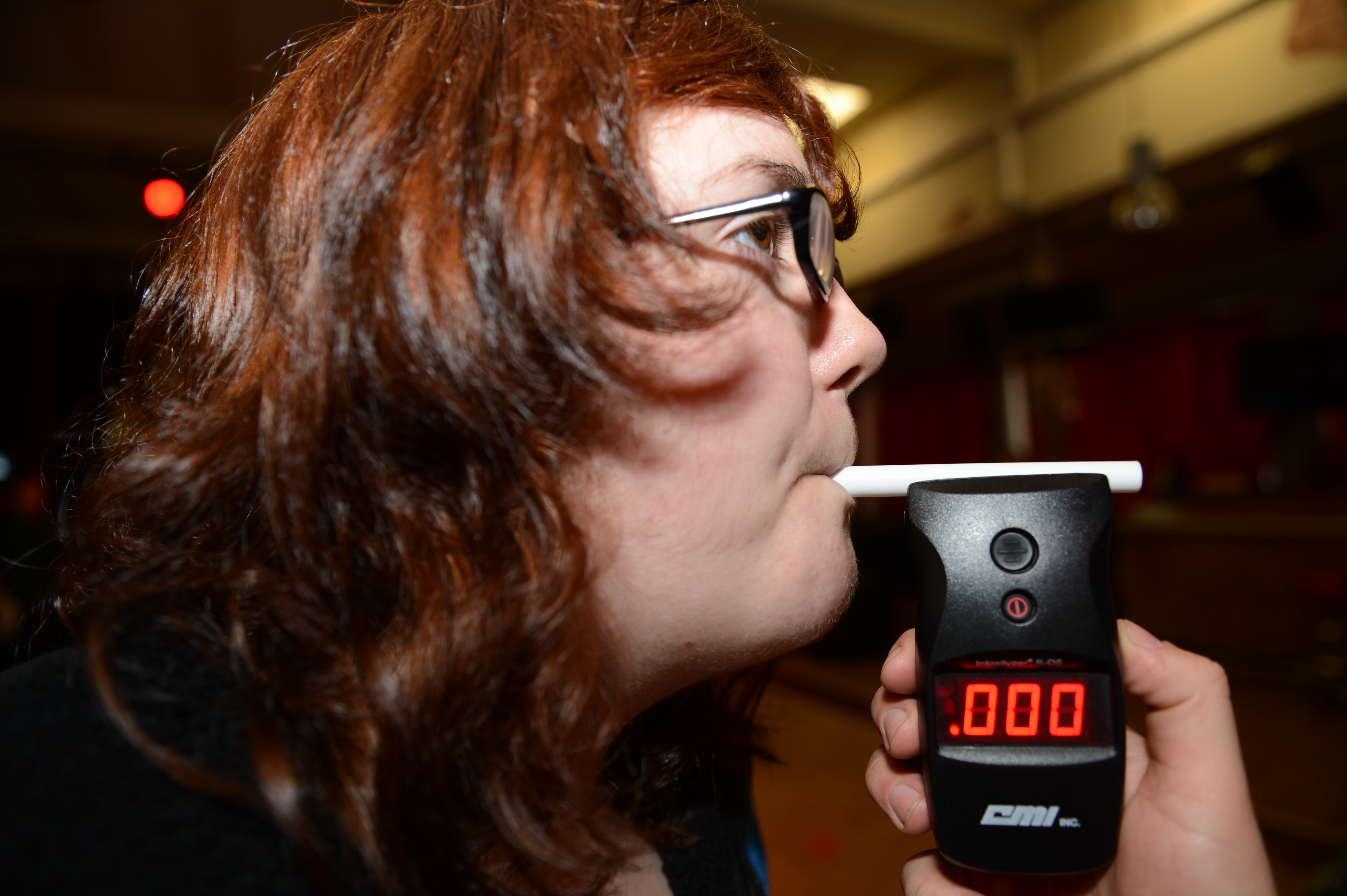 Woman blowing into breathalyzer.