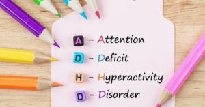 Lettered blocks aligned vertically on a piece of paper spelling ADHD. On the paper are the words "Attention Deficit Hyperactivity Disorder." Each starting letter is written in a different color and the paper is surrounded by colored pencils of assorted colors. Data is associating ADHD and addiction.