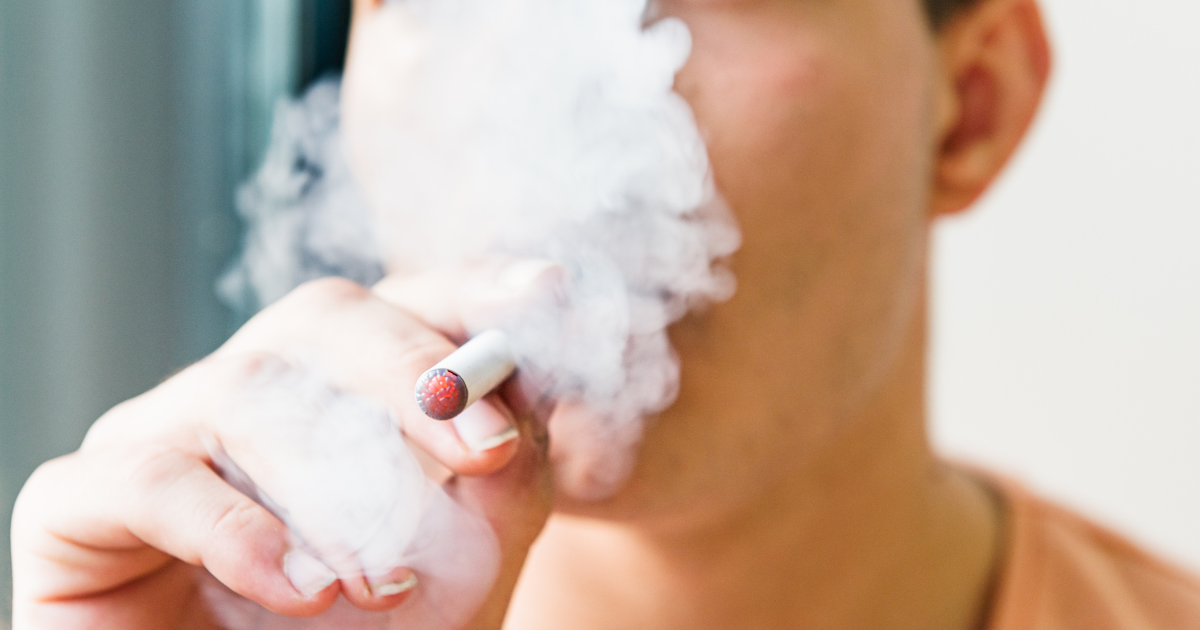 a teenager smokes an e-cigarette full of nicotine