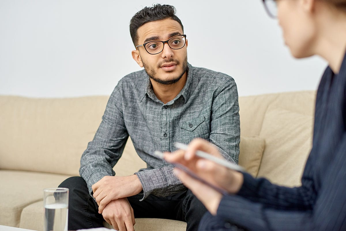 young man asking an addiction treatment specialist in an office setting, "Does marijuana affect cognition long-term?"