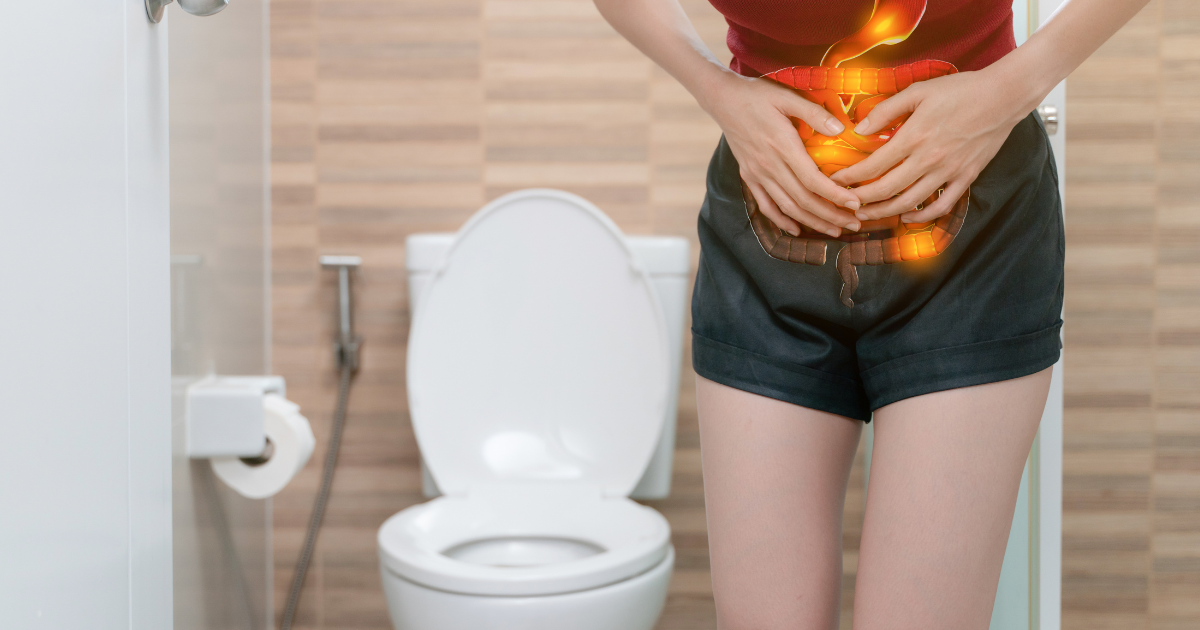 a woman holds her stomach in the bathroom feeling diarrhea caused by quitting alcohol