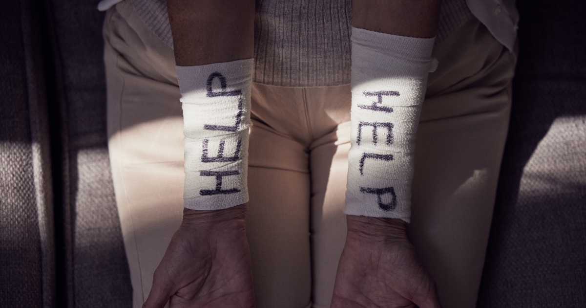 a woman struggling with mental health and substance abuse shows bandages on her wrists that say help me
