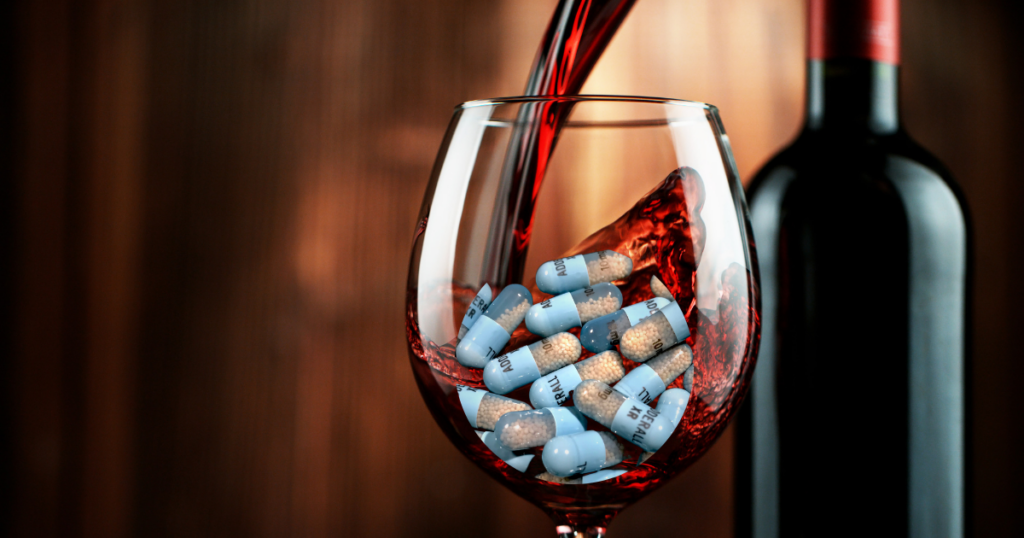 a glass of wine alcohol is poured on top of adderall extended release pills