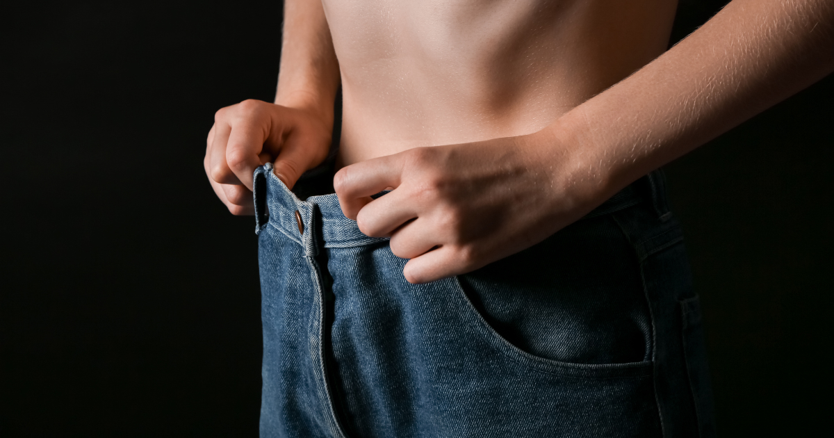 a skinny man holds his jeans that are too big after realizing cocaine is making him lose weight