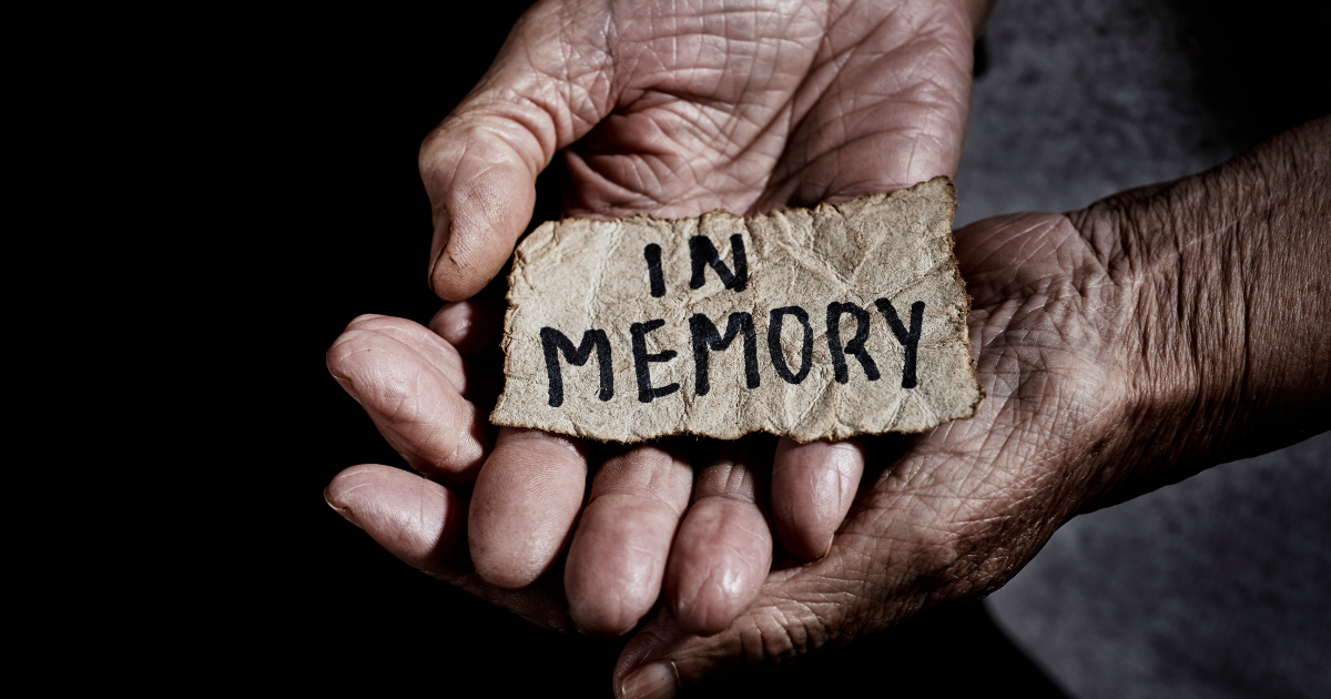 an old man holds a sign that reads in memory