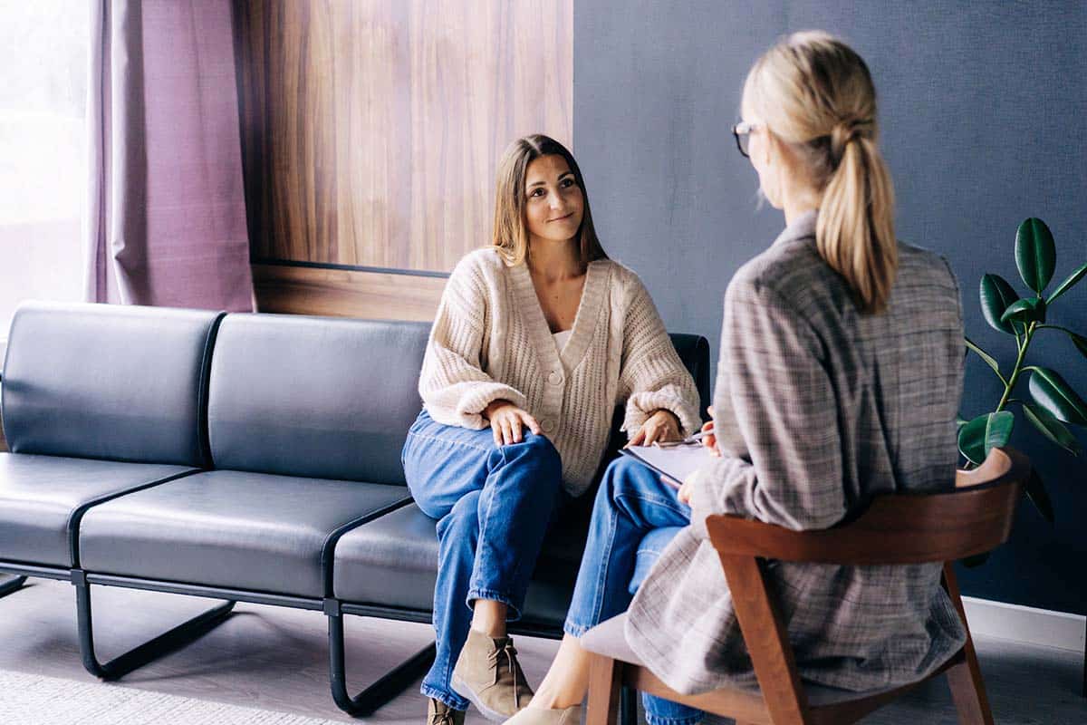 addiction treatment specialist speaking with young woman in an office setting explaining what is AN 627 and how presciption pills can be addictive.