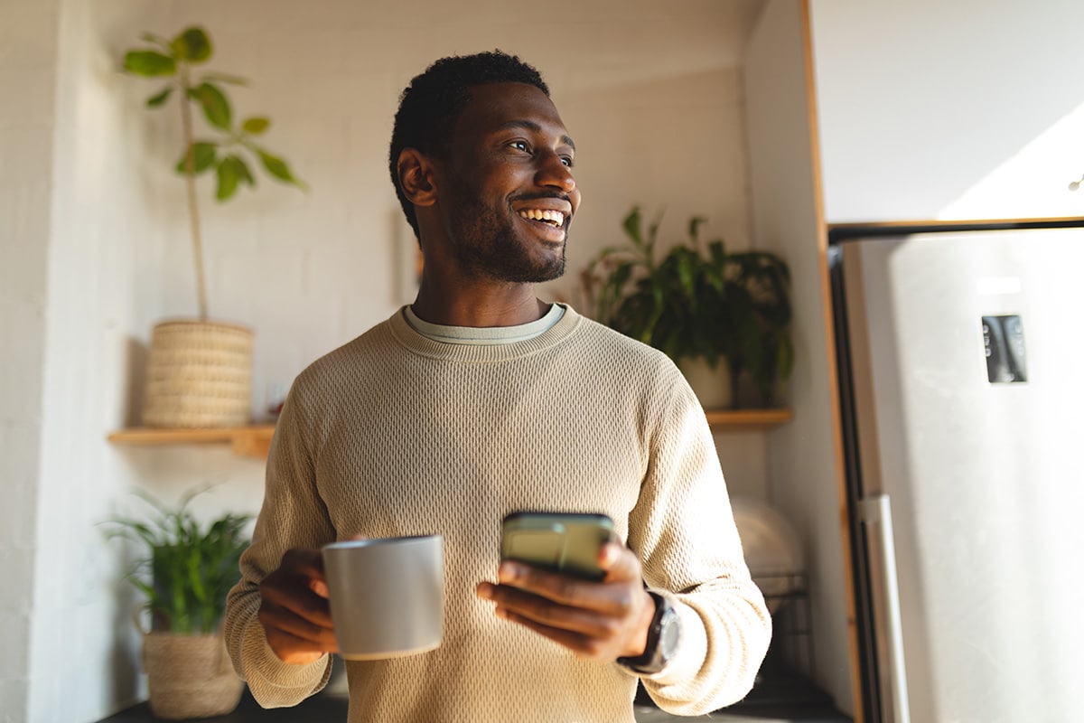 person smiling with coffee and phone looking up teetotaler meaning